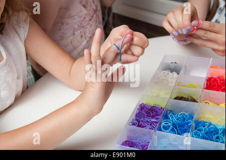 Giovane ragazza che gioca con le bande del telaio sul suo fingures Foto Stock