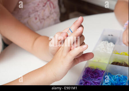 Giovane ragazza che gioca con le bande del telaio sul suo fingures Foto Stock