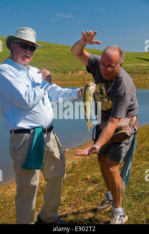 Agriturismo stagni o serbatoi di ranch nel sud del paese collinare spesso produrre lotti di largemouth bass come questi due pescatori discutere. Foto Stock