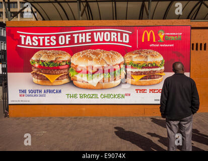 JOHANNESBURG, SUD AFRICA - ristorante McDonald's billboard e l'uomo. I sapori del mondo hamburger promozione. Foto Stock