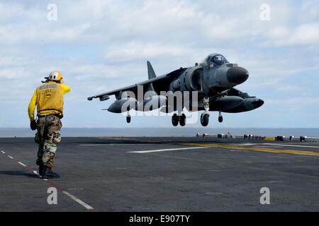 Stati Uniti Aviazione Navale di Boatswain Mate (movimentazione) terza classe Andrew Sterling dirige un marina militare italiana AV-8B Harrier a bordo di aeromobili l'assalto anfibio nave USS Bataan (LHD 5) nel Mare Mediterraneo il 9 ottobre, 2014. Il Bataan anfibio gruppo pronto era cond Foto Stock