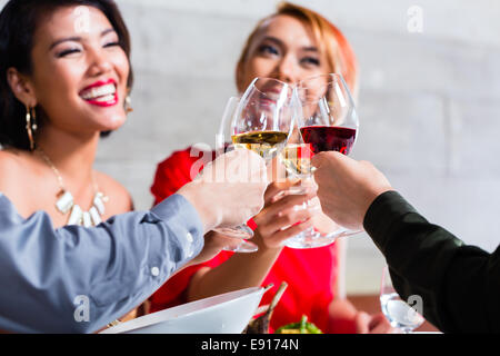 Amici asiatici, due coppie, a pranzo nel ristorante elegante mangiare bene e bere il vino Foto Stock