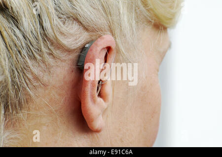 Moderno piccolo hearing aid dietro l'orecchio di una donna Foto Stock