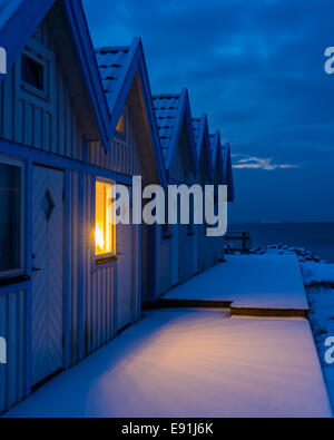 Finestra illuminata in una fila di capanne sulla spiaggia di notte Foto Stock