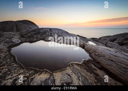 Marea liscia piscina circondata dal rock al tramonto Foto Stock