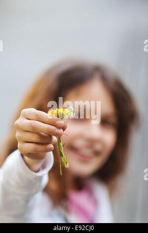 Ragazza giovane presenta un fiorellino Foto Stock