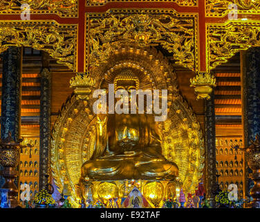 Shiny colore giallo dorato sulla statua di Buddha dominare e ciechi il visitatore. Foto Stock