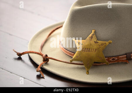 Il cappello da cowboy con Sheriff badge su sfondo di legno in formato orizzontale con il fuoco selettivo Foto Stock