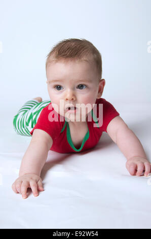 9 mese fa baby boy tenendo la sua testa indossando i colori di Natale Foto Stock