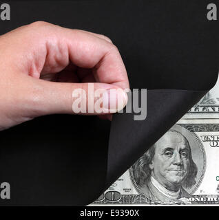 Donna girando a mano una pagina nera e 100 dollar banconota. Foto Stock