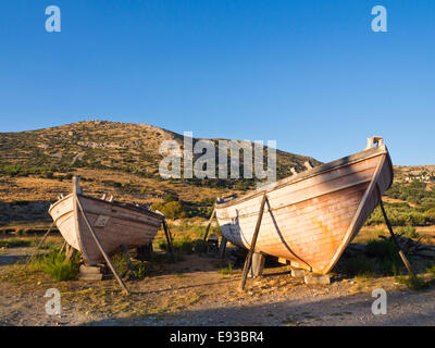 Greco di pesca in legno barca carene collocati come decorazione sul ciglio della strada, golden luce della sera la colorazione della campagna, Samos Grecia Foto Stock