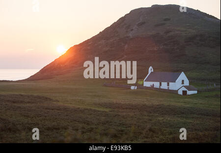 La Chiesa al Mwnt,sulla costa sopra Cardigan Bay,Ceredigion,West Wales.Mwnt è la collina triangolare mound.Il tramonto da caravan park. Foto Stock