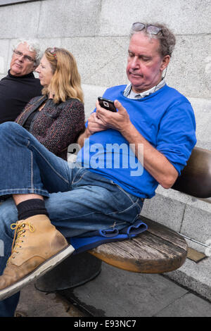 Street photography colpi di persone che utilizzano i loro telefoni mobili in Londra, Regno Unito Foto Stock