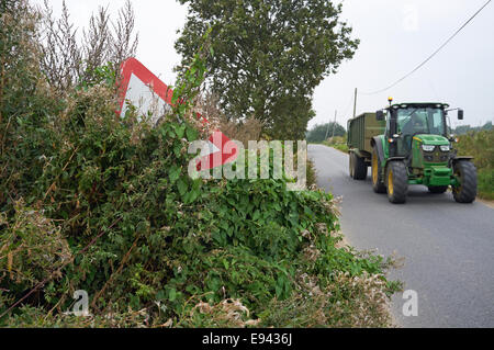 I pericoli della guida su strade rurali, segni nascosti e lenta e grandi veicoli agricoli Foto Stock