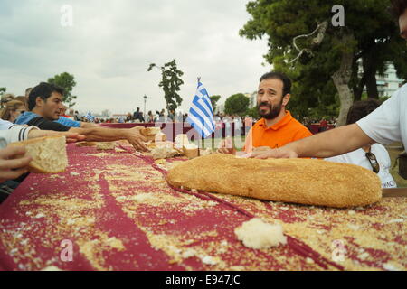 Salonicco, Grecia. Xix oct, 2014. La gente ottenere gratuitamente il pane alla fine dell'evento. Fornai dalla Grecia settentrionale costruita una lunga 150 metri 'koulouri' (un tradizionale greco di sesamo-pane rivestito) di Salonicco, Grecia la seconda più grande città. Il bakers circondato la città iconici Torre Bianca al fine di ottenere un record da guiness dei mondi koulouri più lunga mai fatto Credito: Orhan Tsolak /Alamy Live News Foto Stock