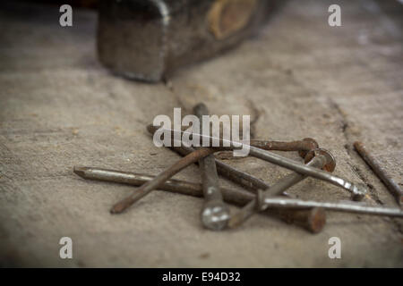 Vecchi chiodi arrugginiti e un martello su sfondo di legno Foto Stock