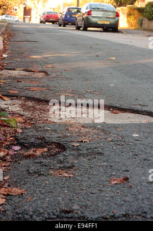 Una pentola di grandi dimensioni foro su una strada con auto parcheggiate in background Foto Stock