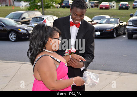 Giovane uomo aiutando la sua data con un corpino a thei high school prom Foto Stock