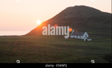 La Chiesa al Mwnt,sulla costa sopra Cardigan Bay,Ceredigion,West Wales.Mwnt è la collina triangolare mound.Il tramonto da caravan park. Foto Stock