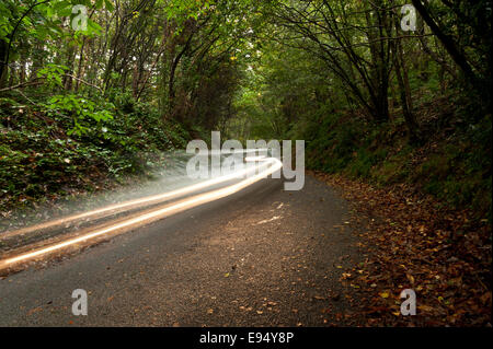 Appeso a mezz aria sentieri delle luci auto passando sopra scuro paese stretto di una singola corsia di pioggia noiosa nuvoloso giorno Foto Stock