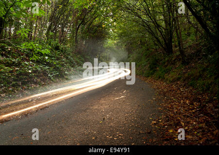 Appeso a mezz aria sentieri delle luci auto passando sopra scuro paese stretto di una singola corsia di pioggia noiosa nuvoloso giorno Foto Stock