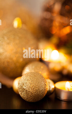 Caldo oro e rosso il Natale a lume di candela con sottofondo di masterizzazione luci tè tra oro casuale e baubles rosso in un caldo incandescente Foto Stock