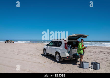 Tourist in piedi accanto a un SUV sulla costa della Namibia nei pressi di Swakopmund, Regione di Erongo, Namibia Foto Stock