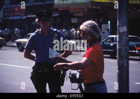 NYPD officer con armatura non e solo un revolver in discussione con un fotografo di strada dotato di una polaroid Foto Stock