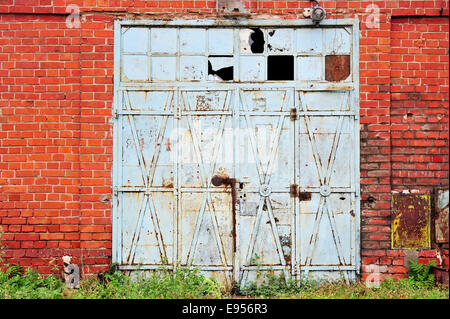 Vecchie e arrugginite blue iron gate da un abbandonato brick warehouse Foto Stock