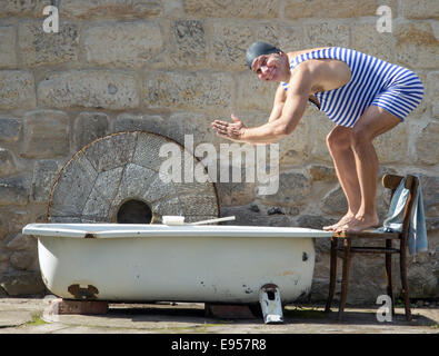 Uomo in costume da bagno retrò salta alla vasca da bagno esterna Foto Stock