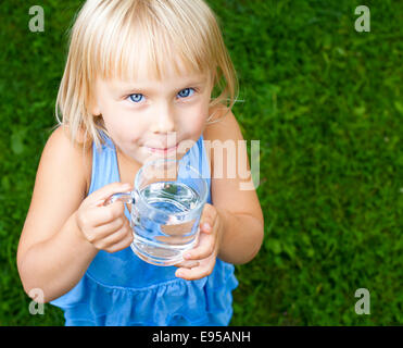 Bambina tenendo un bicchiere di acqua all'esterno Foto Stock