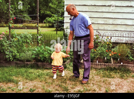 Nonno aiutando toddler nipote di camminare Foto Stock