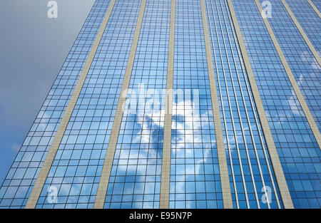 Blu scuro e cielo nuvoloso è riflessa nel vetro di un edificio per uffici. Foto Stock