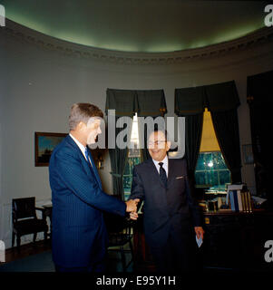Questa fotografia cattura il presidente John F. Kennedy con un visitatore, scattato alla JFK Presidential Library. L'immagine riflette un momento storico durante la presidenza di Kennedy, mostrando l'interazione tra il presidente e un ospite. Foto Stock