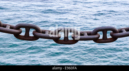 Grande in acciaio arrugginito marrone le maglie della catena contro l'acqua. Foto Stock