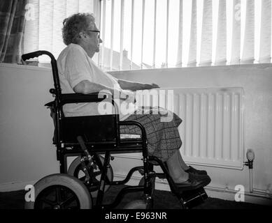 Donna di novanta anni con mano sul radiatore che guarda fuori dalla finestra. REGNO UNITO. Coronavirus, autoisolamento, distanza sociale, quarantena... concetto Foto Stock