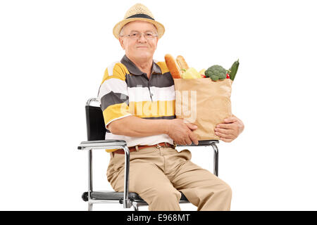 Senior tenendo un sacchetto shopper seduto nella sedia a rotelle isolati su sfondo bianco Foto Stock