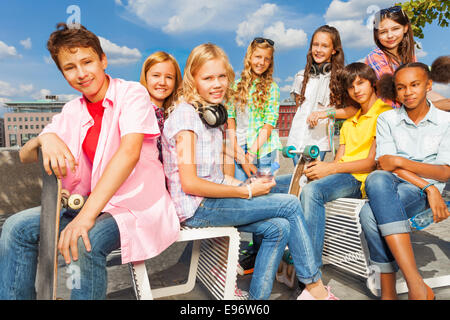 Un gruppo di bambini seduti su sedie bianche con skateboard Foto Stock