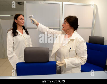 Praga, Repubblica Ceca. Xxi oct, 2014. Il personale medico dimostra tenendo la temperatura di un passeggero a Vaclav Havel Aeroporto di Praga Repubblica Ceca, Ottobre 21, 2014. Repubblica ceca introduce lo screening di passeggeri negli sforzi tesi a prevenire la diffusione del virus di Ebola. Credito: Roman Vondrous/CTK foto/Alamy Live News Foto Stock