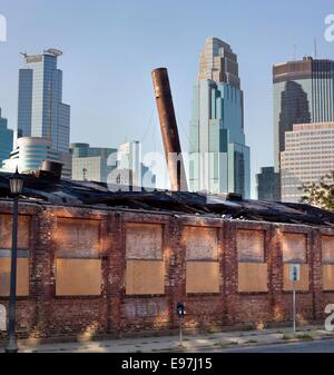 Il vecchio edificio di mattoni con fumaiolo pendente nello storico quartiere di magazzino con i grattacieli del centro di Minneapolis, MN, Stati Uniti d'America Foto Stock