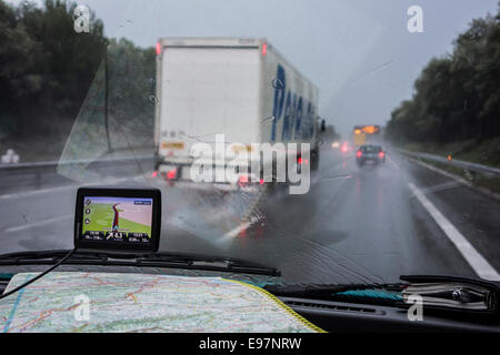 Accelerare il carrello il sorpasso di vetture su autostrada durante heavy rain shower visto dall'interno della vettura con GPS e road map sul cruscotto Foto Stock