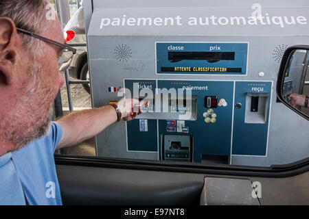 Driver in auto mettendo in biglietteria automatica / sistema Electronic Toll Collection macchina prima di effettuare il pagamento con carta di credito al casello autostradale Foto Stock