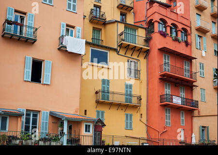 Balconi e finestre con tendine di color pastello delle case nella città di Menton lungo la Riviera Francese, Côte d'Azur, in Francia Foto Stock