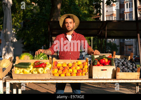 Giovane uomo per la vendita di frutta e verdura al mercato in stallo Foto Stock