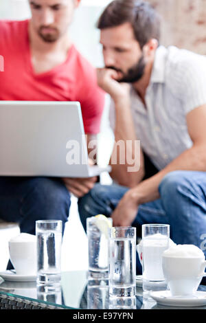 Due maschi gli studenti universitari in cafe lavorando sul computer portatile Foto Stock