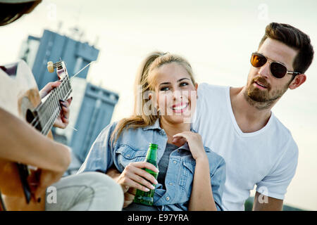 I giovani ascoltando chitarrista al partito sul tetto Foto Stock