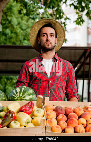 Giovane uomo per la vendita di frutta e verdura al mercato in stallo Foto Stock