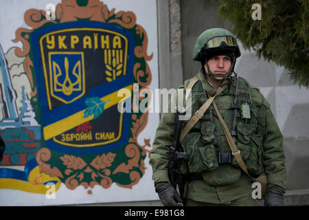 Armati soldato russo sta di guardia di fronte ad una Ucraina insegne al di fuori del Perevalne base militare nei pressi di Simferopol Crimea Foto Stock