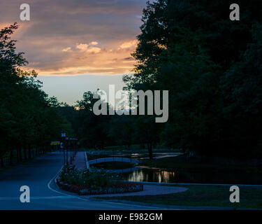 Vista tramonto park in Massachusetts. Sulla destra sono piscine riflettenti small foot bridge andando sulla sinistra è strada alberata. sky è Foto Stock