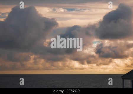 Estremamente grande blu grigio nuvole oceano a sbalzo. Caldo bagliore arancione dietro le luci da sole l'impostazione. Luce celeste è il cloud Foto Stock